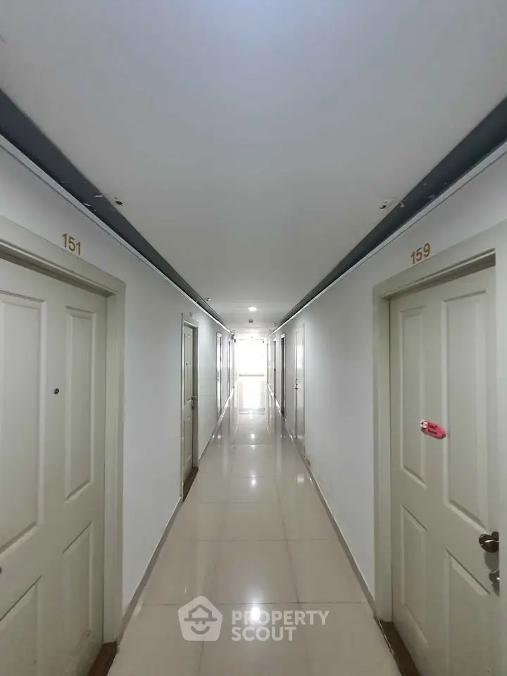 Bright and clean apartment corridor with numbered doors and polished tile flooring.