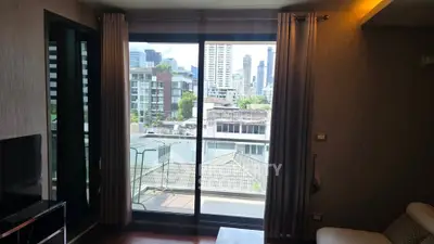 Modern living room with large window offering stunning city view in urban apartment.