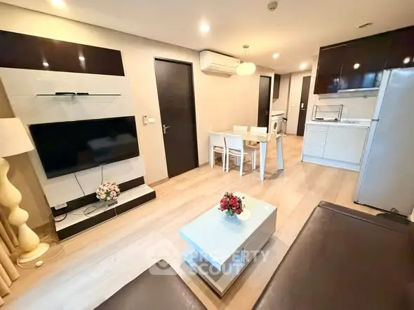 Modern open-plan living room with sleek kitchen and dining area, featuring contemporary furniture and stylish decor.