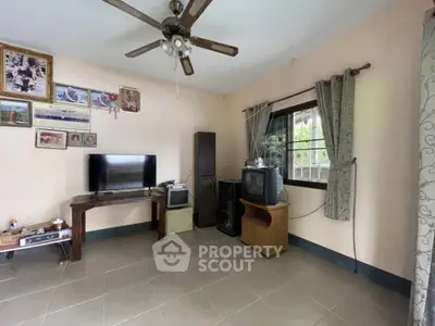 Cozy living room with ceiling fan, TV, and decorative wall art.