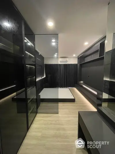 Sleek modern bedroom with glossy black built-in wardrobes and a minimalist design, featuring a platform bed and ambient lighting.