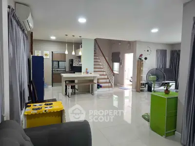 Spacious open-plan living room with modern kitchen and staircase, perfect for family gatherings.