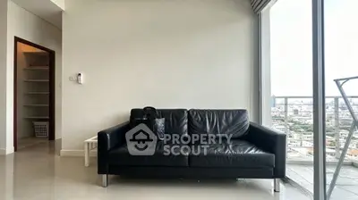 Modern living room with black leather sofa and city view balcony.