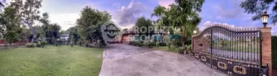 Spacious garden with elegant gated entrance in serene residential area.