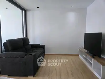 Modern living room with sleek black sofa and flat-screen TV on wooden floor