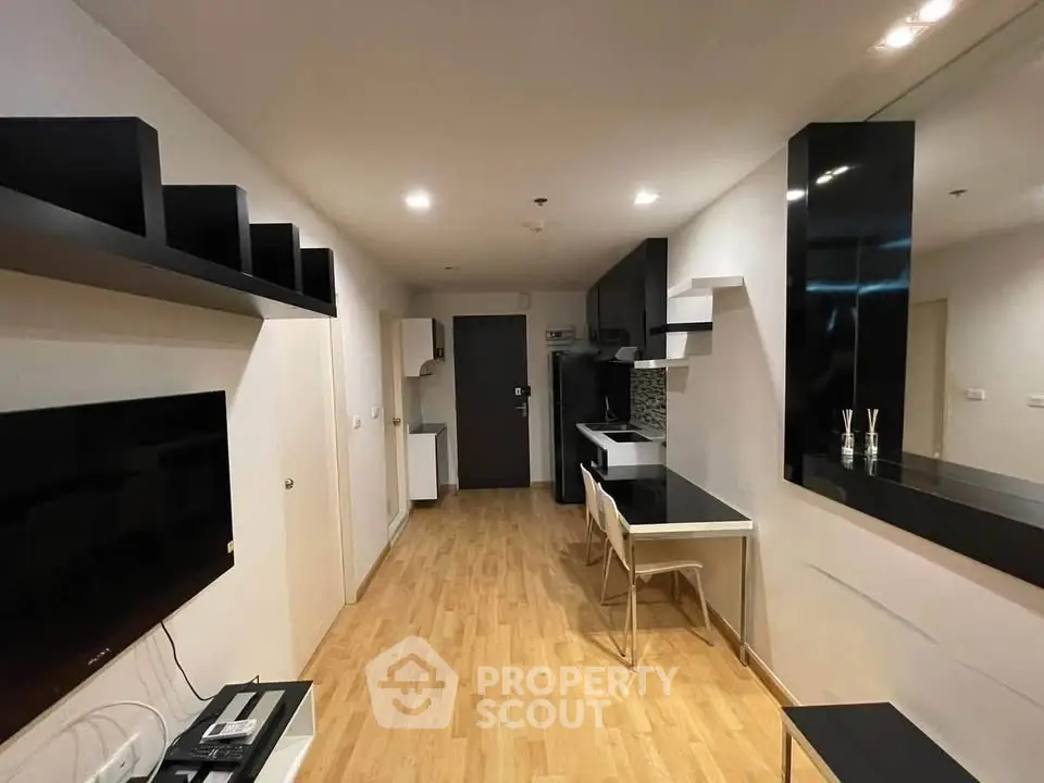 Modern apartment interior with sleek black and white decor, featuring a compact kitchen and stylish shelving.