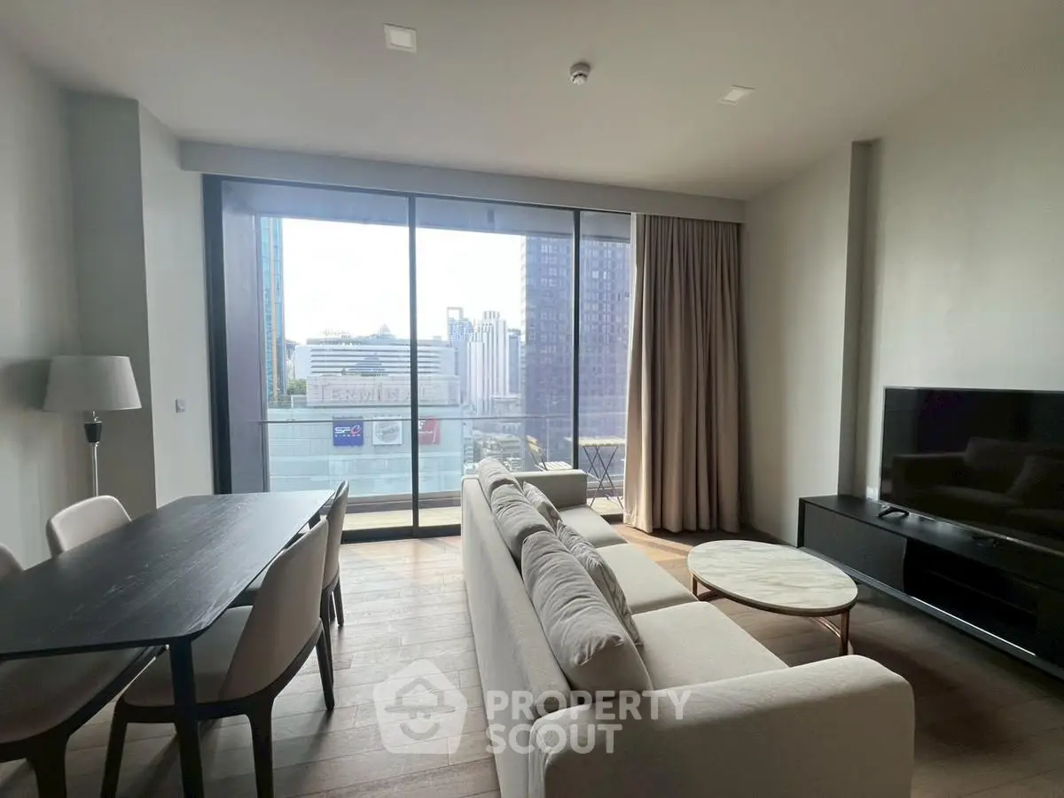 Modern living room with large windows and city view, featuring stylish furniture and a cozy atmosphere.