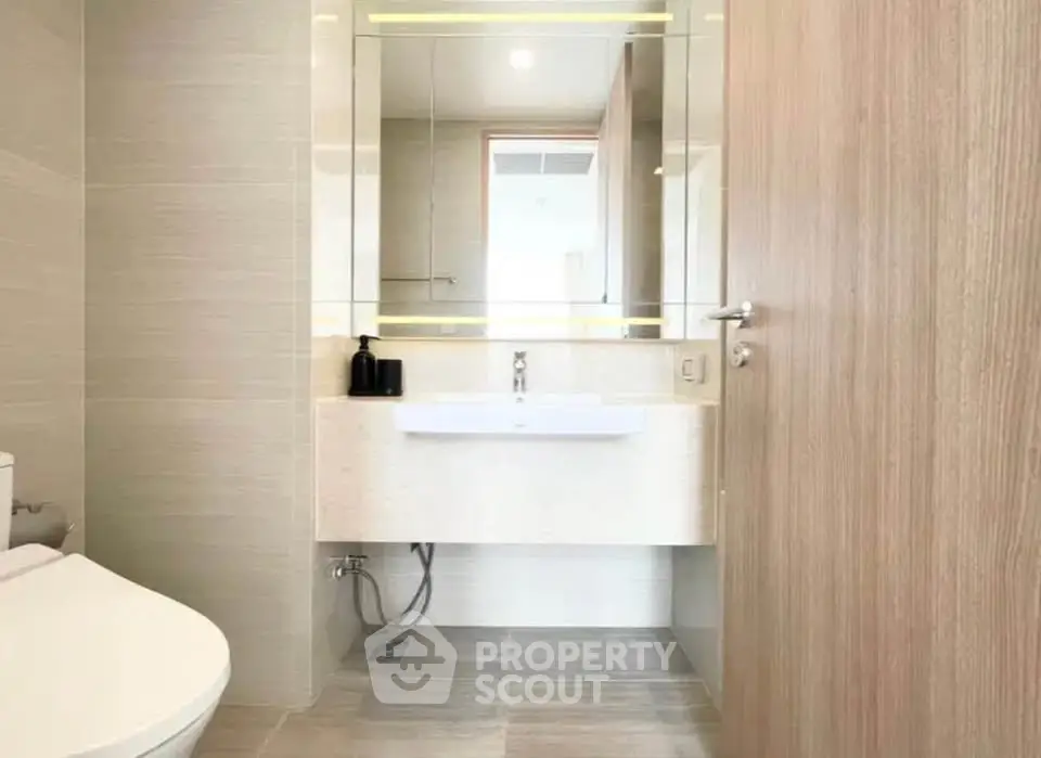 Modern bathroom with sleek fixtures and large mirror in a contemporary apartment.