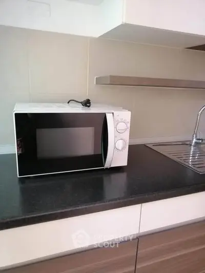 Modern kitchen with microwave on sleek countertop and stainless steel sink