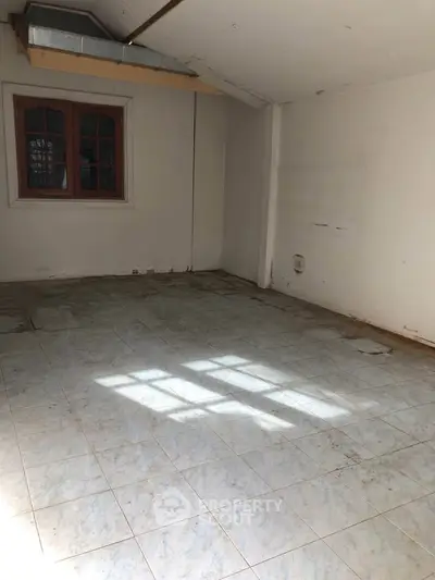 Spacious empty room with tiled floor and window, ideal for customization.