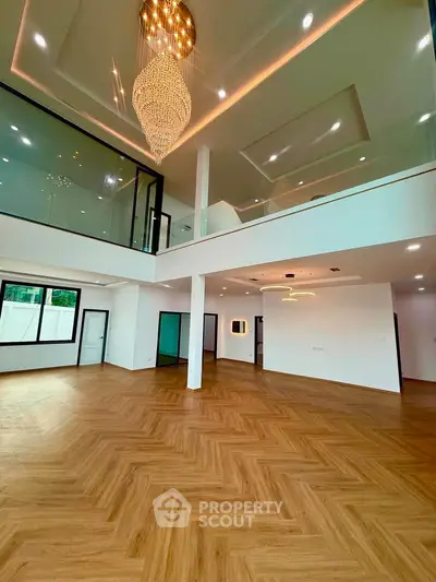 Luxurious open-plan living room with high ceilings and elegant chandelier in modern home.