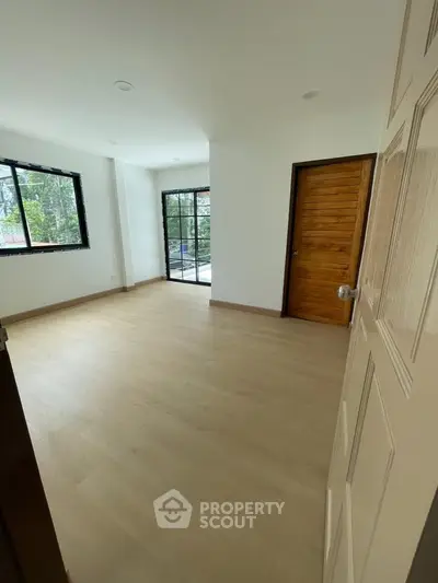 Spacious empty room with large windows and wooden door, perfect for customization.
