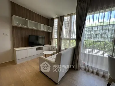 Modern living room with large windows and stylish furniture in a high-rise apartment.