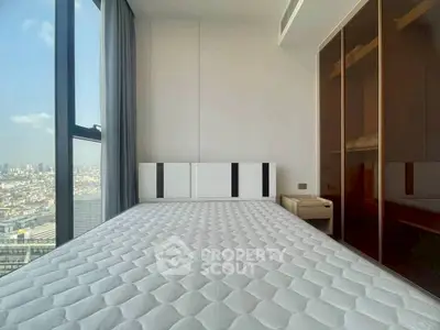 Modern bedroom with city view, large window, and sleek wardrobe in a high-rise apartment.