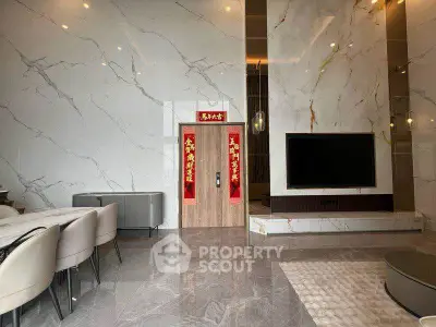 Luxurious modern living room with marble walls and large flat-screen TV, elegant dining area, and stylish decor.