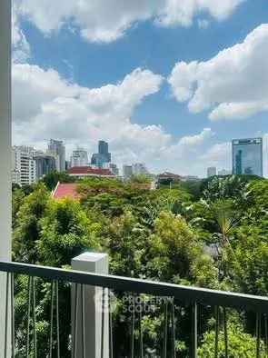 Stunning cityscape view from a balcony overlooking lush greenery and skyline.