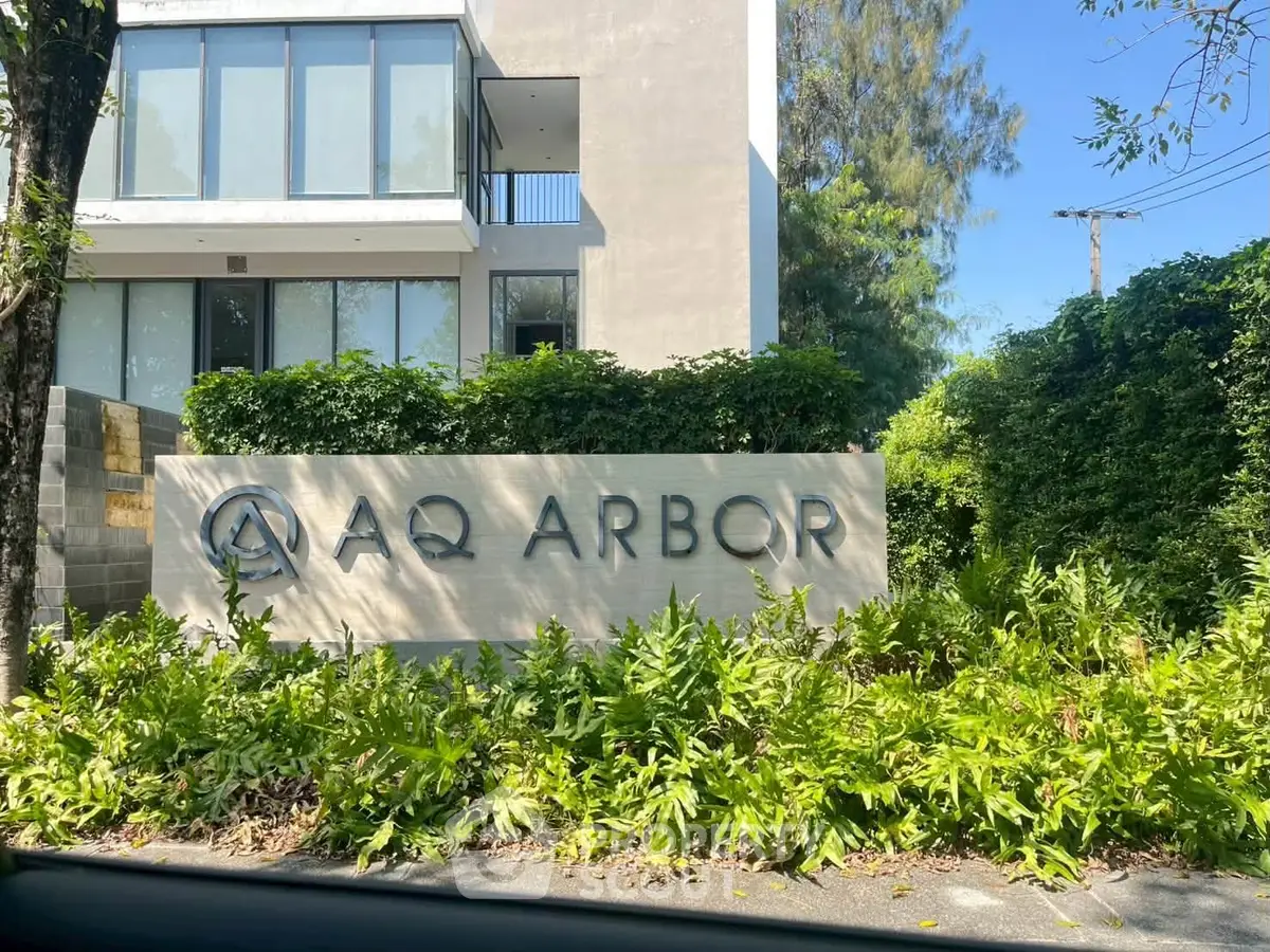 Modern building exterior with lush greenery and prominent AQ Arbor signage.