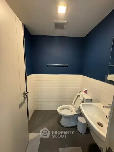 Modern bathroom with blue accent wall and white fixtures in a contemporary home.