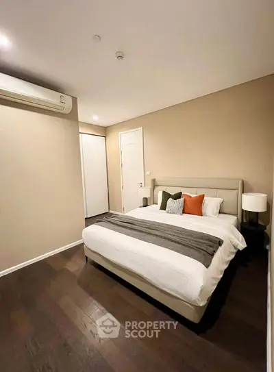 Modern bedroom with stylish decor and hardwood floors, featuring a cozy bed and ambient lighting.