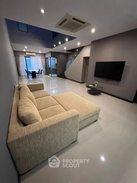 Spacious modern living room with elegant beige sofa and wall-mounted TV