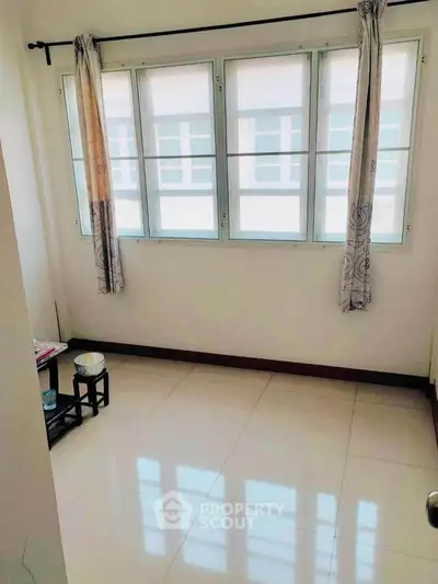 Bright room with large windows and tiled flooring, perfect for a cozy living space.