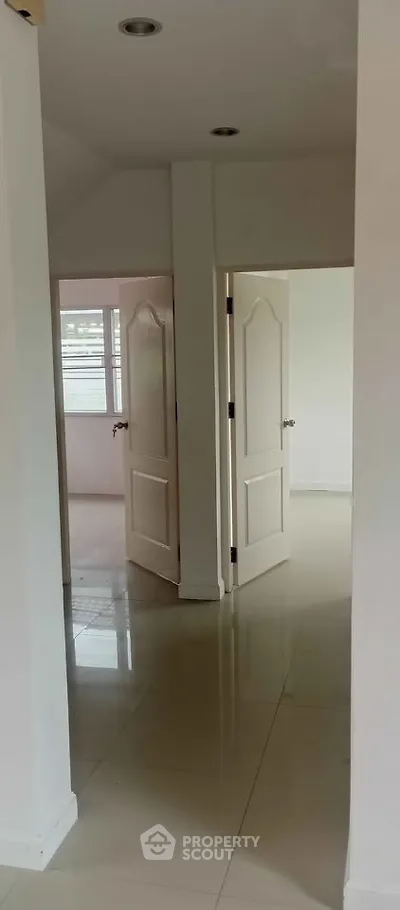 Spacious hallway with glossy tiled floors and open doors leading to bright rooms.