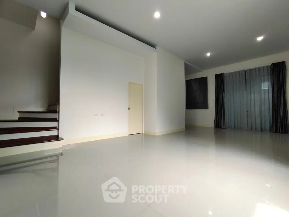 Spacious modern living room with glossy tile flooring and staircase