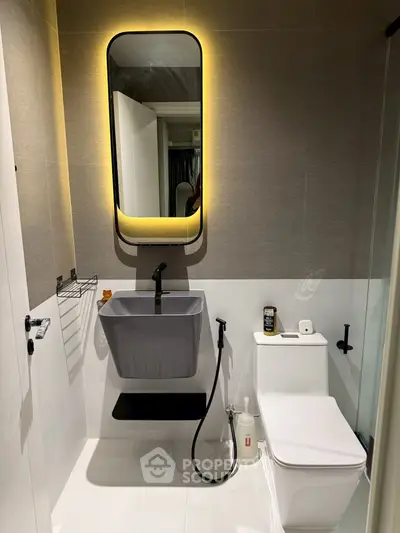 Modern bathroom with sleek fixtures and ambient lighting, featuring a stylish mirror and contemporary sink design.