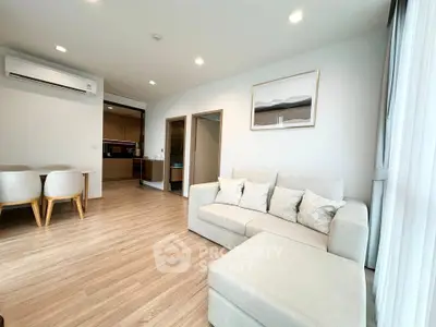 Spacious modern living room with cozy sofa and dining area, featuring sleek wooden flooring and ample natural light.