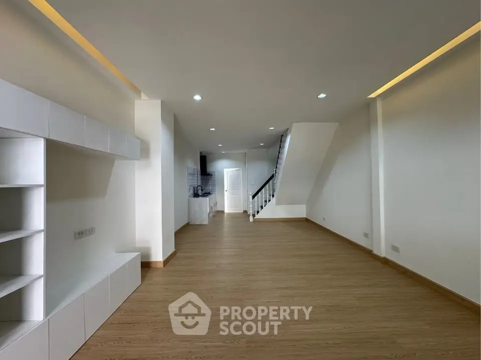 Spacious modern living room with wooden flooring and built-in shelves