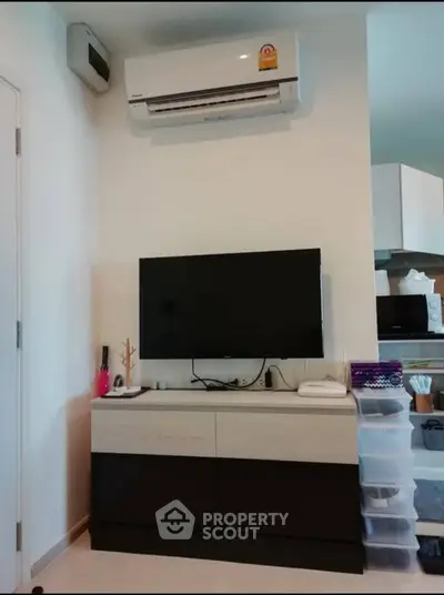 Modern living room with wall-mounted TV and air conditioning unit, featuring sleek storage solutions.