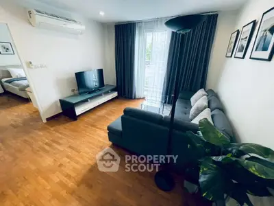 Modern living room with stylish decor and natural light, featuring a cozy sofa and flat-screen TV.