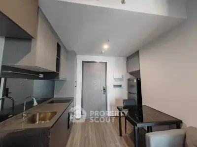 Modern compact kitchen with sleek cabinetry and dining area in a stylish apartment.