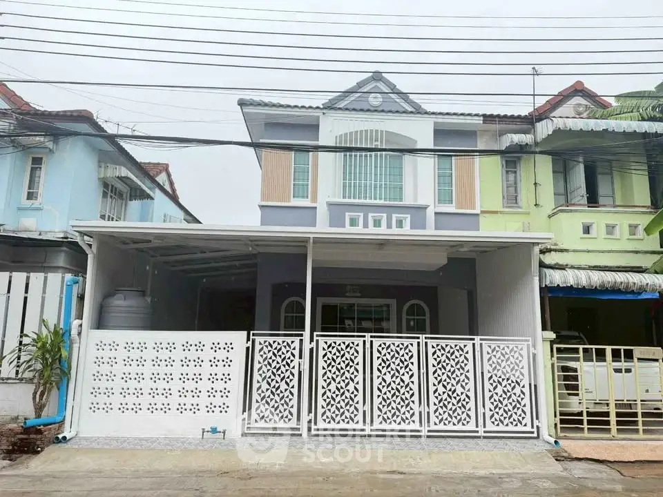 Charming two-story townhouse with modern facade and gated entrance in a serene neighborhood.