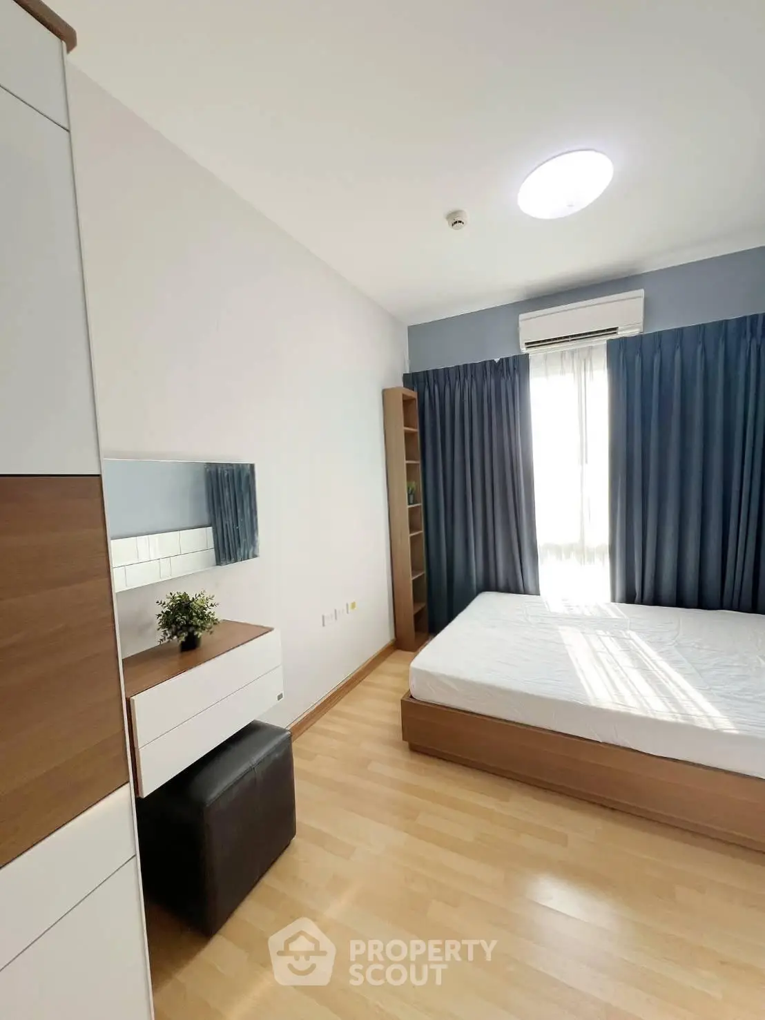 Modern bedroom with natural light, wooden flooring, and stylish furniture in a cozy apartment.