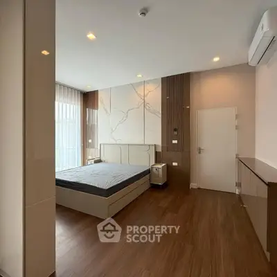 Modern bedroom with sleek design and wooden flooring, featuring a large bed and stylish decor.