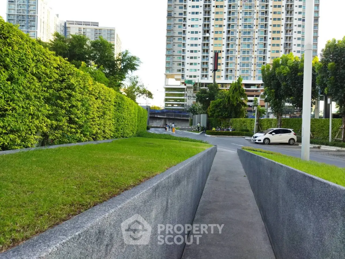 Modern urban residential complex with lush greenery and paved pathways.