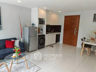 Modern open-plan living room with kitchen, featuring sleek appliances and stylish decor.