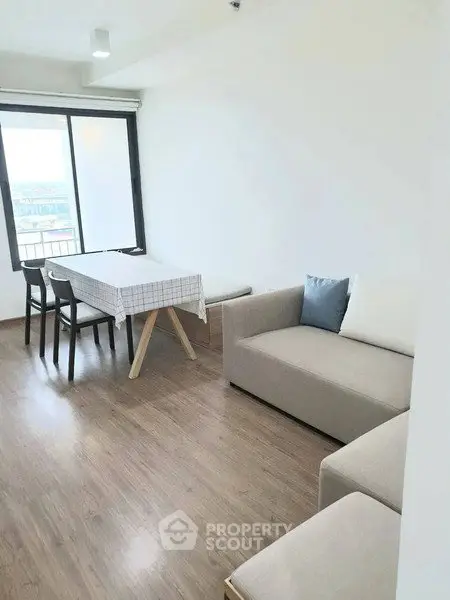 Bright living room with modern furniture and large window offering city view.