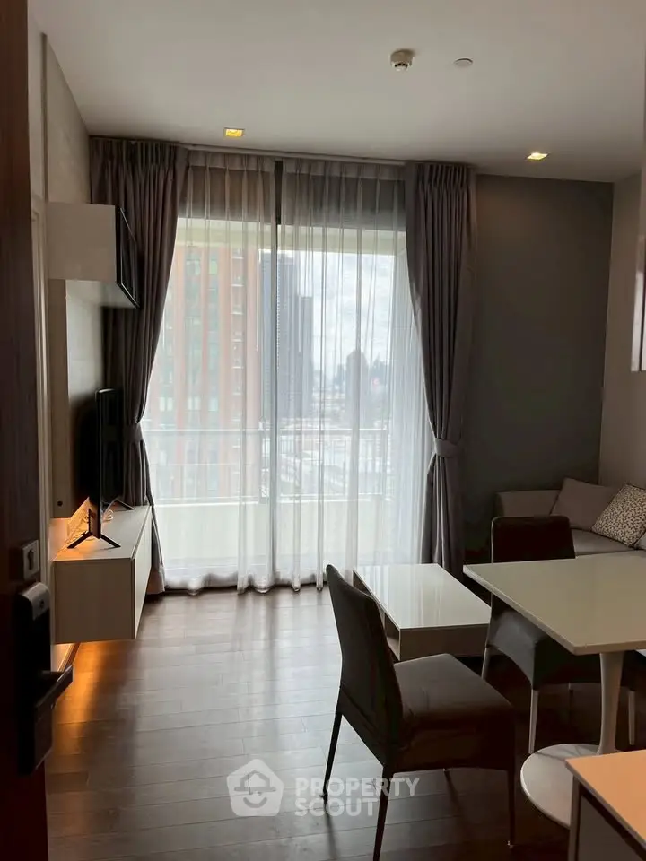 Modern living room with large windows and stylish furniture in a high-rise apartment.