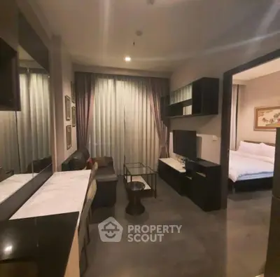 Modern living room with sleek furniture and adjacent bedroom in a cozy apartment.