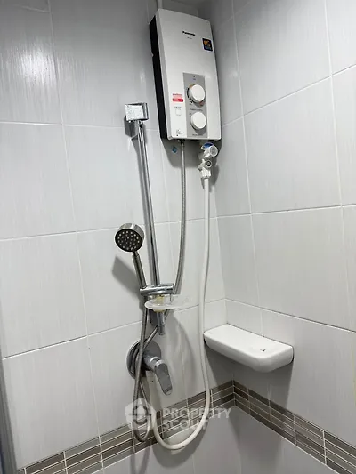 Modern bathroom with sleek shower and water heater, featuring elegant tile design.