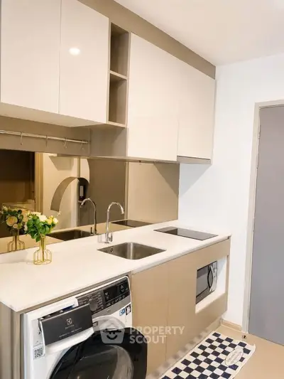 Modern kitchen with sleek cabinetry and built-in appliances, featuring a washing machine and elegant decor.