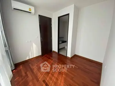 Spacious room with wooden flooring and air conditioning, ideal for customization.