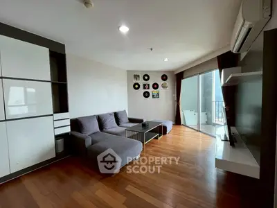 Spacious modern living room with wooden floors, large sofa, and balcony access in a stylish apartment.