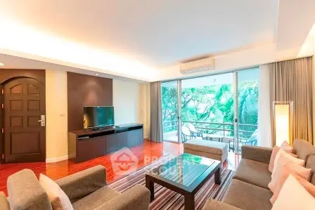 Spacious living room with modern decor and large windows overlooking a lush green view.