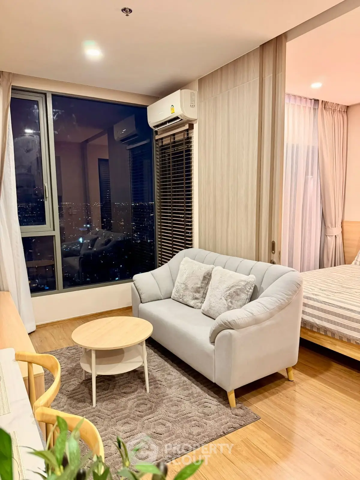 Modern living room with city view, cozy sofa, and stylish decor in a high-rise apartment.