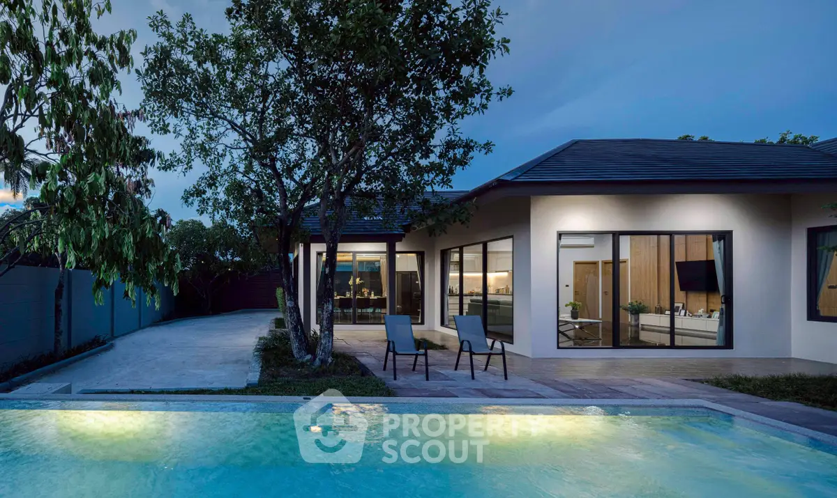 Luxurious modern home with illuminated pool and spacious patio at dusk, perfect for relaxation and entertainment.