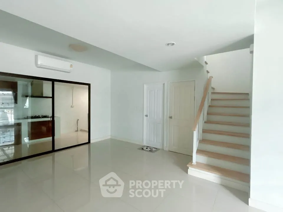 Spacious modern living room with staircase and glass kitchen partition