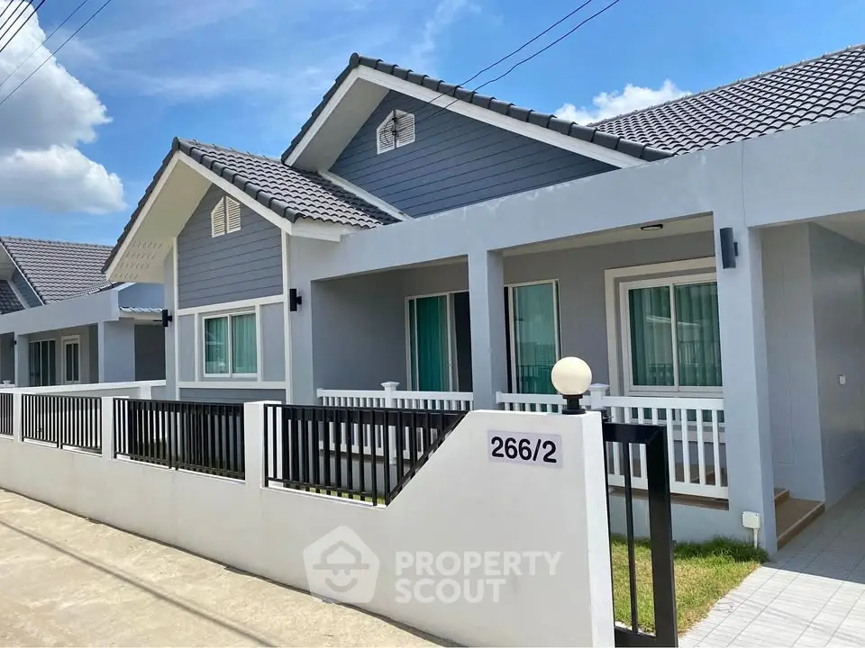 Charming modern house with a sleek design, featuring a fenced front yard and inviting porch.